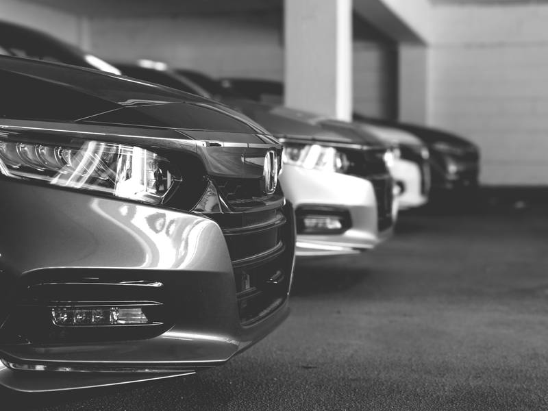A row of similar sedans parked side by side, in black and white